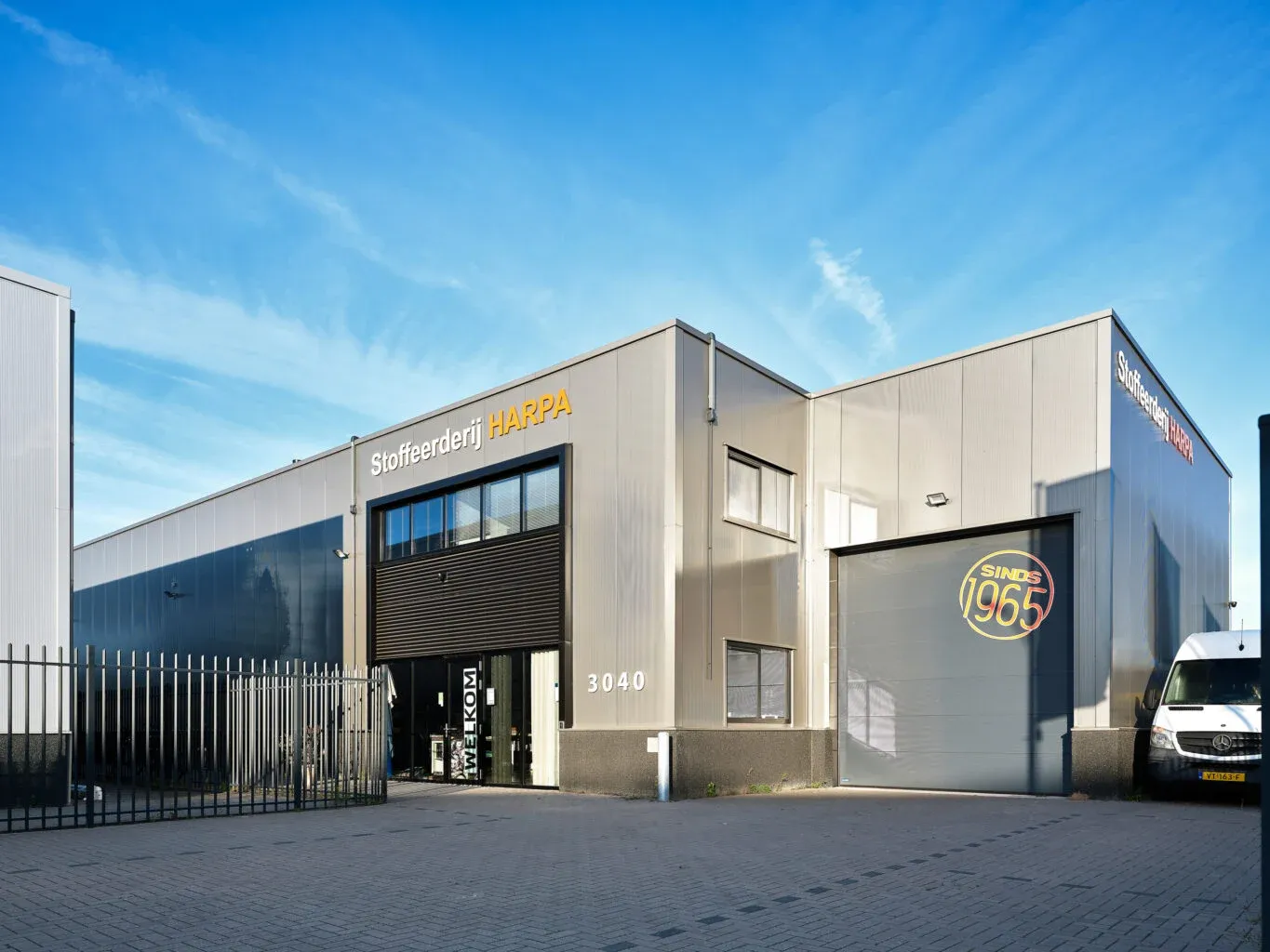 Het bedrijfspand van Stoffeerderij HARPA met de ingang en het sinds 1965-logo op de gevel