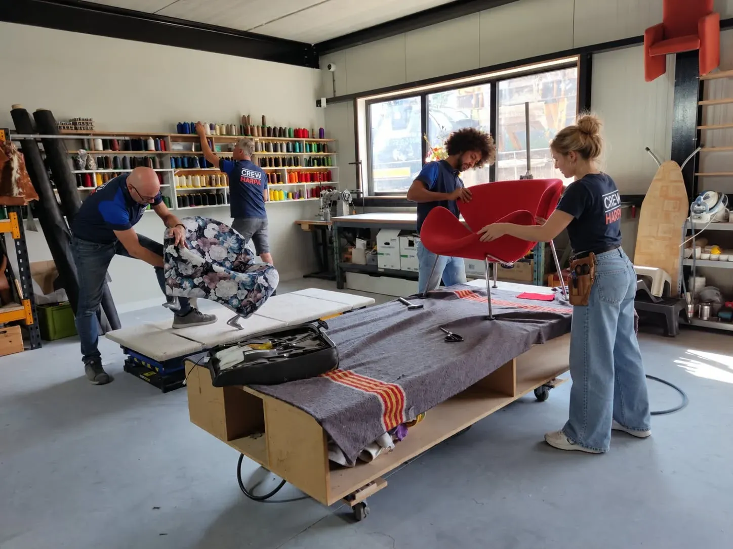 Het HARPA-team werkt samen aan het bekleden van fauteuils in de werkplaats