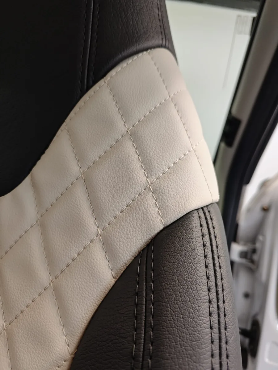 Detail van antraciet-crème bekleding met ruitstiksel