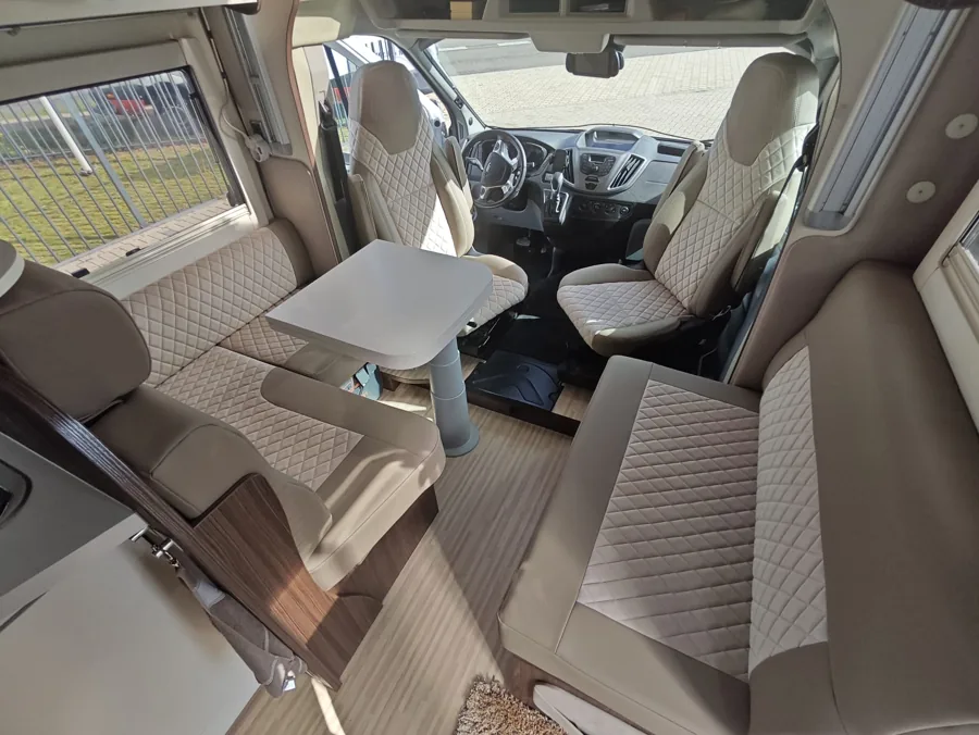 Camperinterieur met licht doorgestikte stoelen en zitgroep