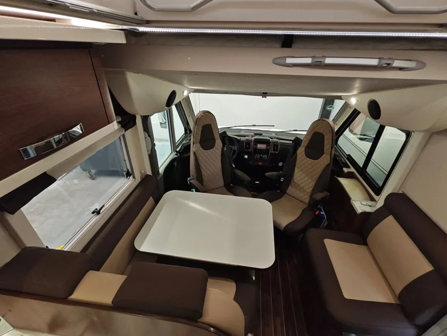 Camperinterieur met bruin-crème voorstoelen en zitbanken